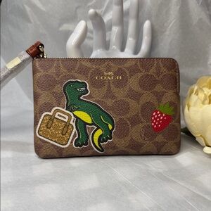 COACH CORNER ZIP WRISTLET IN SIGNATURE CANVAS WITH STICKER PRINT DINASOUR